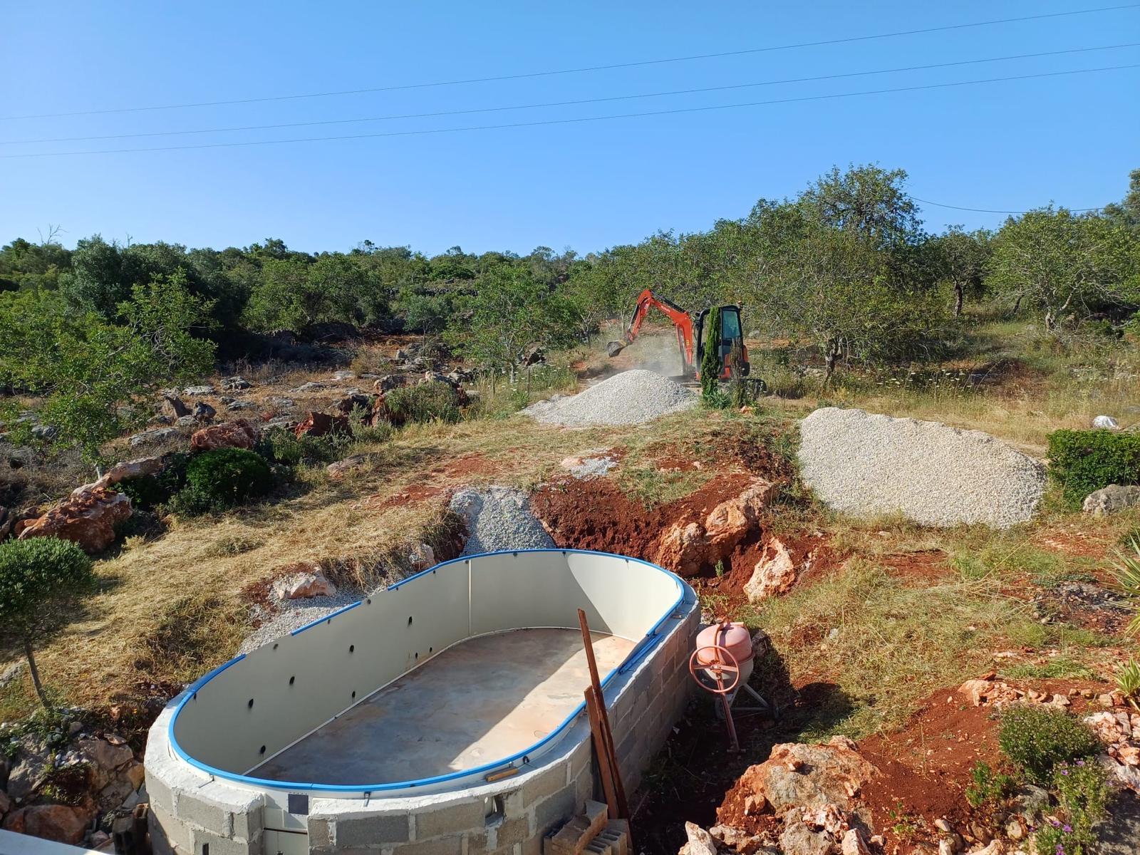 Mini excavator creating planting beds and reshaping a garden in a residential Algarve property
